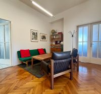 Offices with wooden decor, sofa, armchair, and table. There are paintings on the wall.