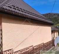 A family house in Reľov with a brown roof and a massive fence.
