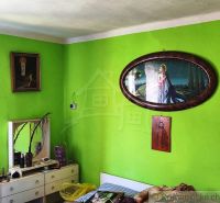 A room in a family house with distinctly green walls and religious paintings.