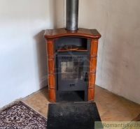 A tiled stove in the corner of a family house with tiles and a carpet pad.