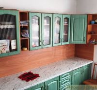 A kitchen unit in a family house with green doors and a marble countertop.