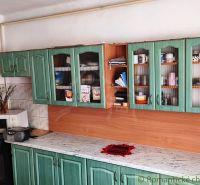 Green kitchen in a family house with a marble countertop and ceramic tiles.