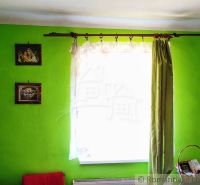 A room in a family house with bright green walls, a curtain, and wall paintings.