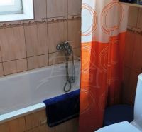 A bathroom in a family house with a shower curtain and a bathtub, ceramic tiles.