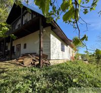 A cottage in Žarnovica surrounded by greenery with a wooden roof and a veranda.