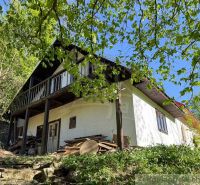 Cottage in Žarnovica with a wooden terrace and trees, peaceful natural environment.