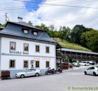 A guesthouse with a restaurant in Žarnovica surrounded by greenery and parked cars.