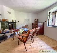 The interior of a cottage with a ceramic stove, retro furniture, and a wooden decor floor.