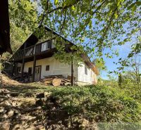 A cottage near Žarnovica surrounded by greenery under a blue sky.