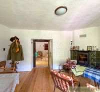 The interior of a cottage with a tiled stove and a wooden decor floor.