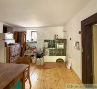 A kitchen with a tiled stove and a wooden decor floor in the cottage.