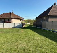 A peaceful garden, surrounded by houses and fences in Pozba, ideal for residential plots.