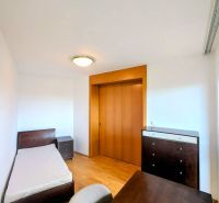 A room with a bed, a table, and a wardrobe in a 4-room apartment with a wooden decor floor.