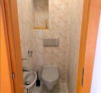 A toilet with a sink in a 4-room apartment, tiled with light ceramic tiles.