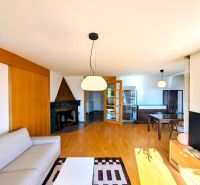 Living room in a 4-room apartment with a fireplace, sofa, and wooden decor flooring.