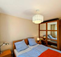 Bedroom in a 4-room apartment with a double bed, wardrobe, and lamp, flooring with a wooden decor.