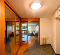 A hallway of a 4-room apartment with a wooden decor floor and built-in wardrobes.