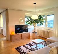 Living room in a 4-room apartment with a wood-decor floor, sofa, and television.