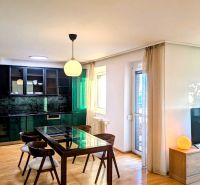 Dining area in a 4-room apartment with a wooden decor floor and a glass table.