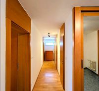A hallway with a light wall and a floor with a wooden decor in a 4-room apartment.