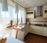 A kitchen in a 2-room apartment with a wooden decor floor and light curtains.
