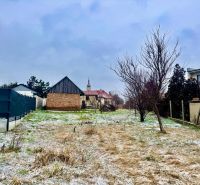 A snowy plot with a house without a facade in Dvorníky, fencing, grassy terrain, blades of grass.