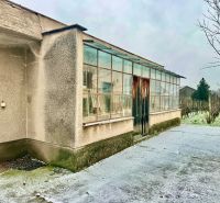A family house in Dvorníky with a glass-enclosed veranda and a concrete walkway.