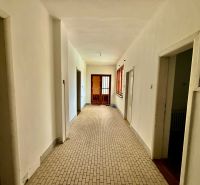 A hallway in a family house with white walls and neutral-colored tiles.