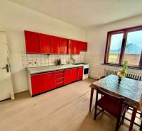 A kitchen in a family house with red cabinets and large windows.