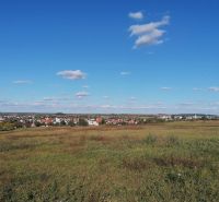 Šenkvice surrounded by agricultural and forest lands under a clear blue sky.