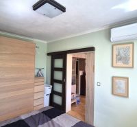 A bedroom with sliding doors, air conditioning, and a wardrobe in a 2-room apartment.