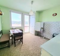 A kitchen in a 3-room apartment with a dining table, green walls, and a tiled wall.