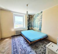 Bedroom with a bed, carpet, forest-themed wallpaper in a 3-room apartment.