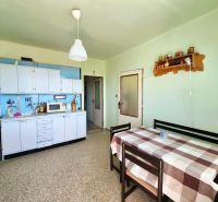 A kitchen with a dining area, white cabinets, and a microwave in a 3-room apartment.