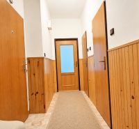 A hallway in a 2-room apartment with wood-paneled walls and tiled flooring.