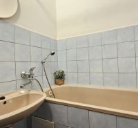 A bathroom in a 2-room apartment with ceramic tiles and a bathtub.