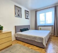 Bedroom in a two-room apartment with a wooden decor floor, decorations, and storage furniture.