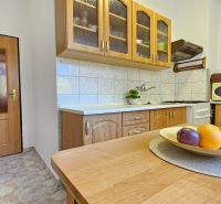 A kitchen in a 2-room apartment with wooden cabinets and fruit on the table.