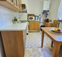 A kitchen in a 2-room apartment with wooden furniture and a white kitchen unit.