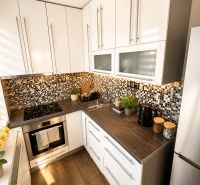 A kitchen in a 3-room apartment with white cabinets and a wood-patterned floor.