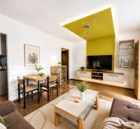 Living room with a sofa, dining table, and wood-patterned flooring.