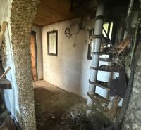 Internal staircase in a cabin with a stone wall and wooden ceiling.