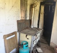 An old stove, a gas cylinder, and cobwebs in the cabin.