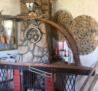 A fireplace in a cottage with rustic stone decor and a wall sconce.