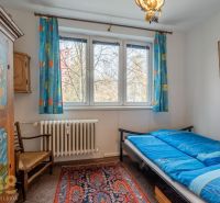 A room in a 4-room apartment with a blue bed and a colorful carpet, bright interior.