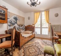 A room in a 4-room apartment with wooden furniture, woven wool, and a large window.