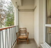 Balcony with a wooden chair and railing in a 4-room apartment.