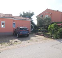 A family house in the town of Vodice, parking space, and a garden with flowers and trees.