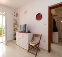 The interior of a family house with white furniture, a television, and open doors to the garden.