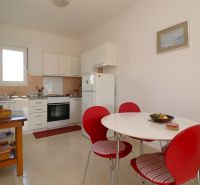 A kitchen in a family house with white furniture and red chairs.